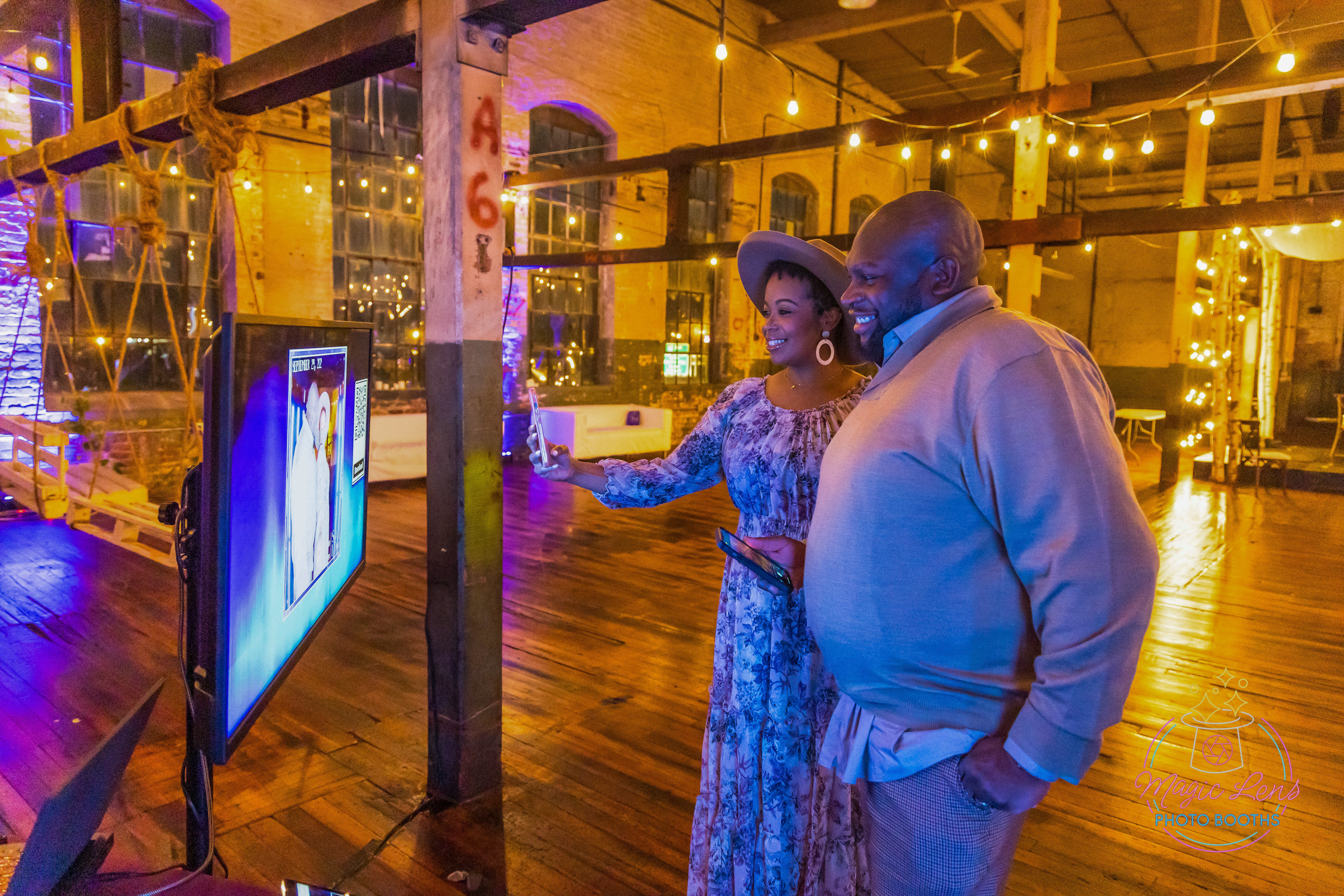 A photo preview with a Qr code on the big screen tv of a pretty couples photo taken on the 360 photo booth